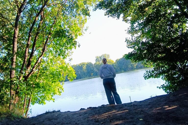 Ich, wie ich an einem See stehe und nach Vorne schaue
