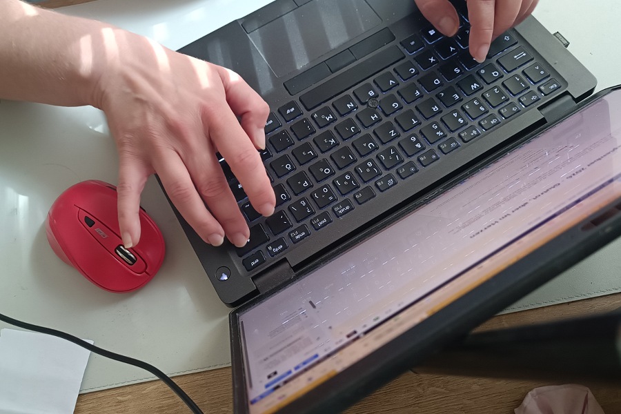 Blick auf die Tastatur eines Laptops und Hände, die darauf tippen